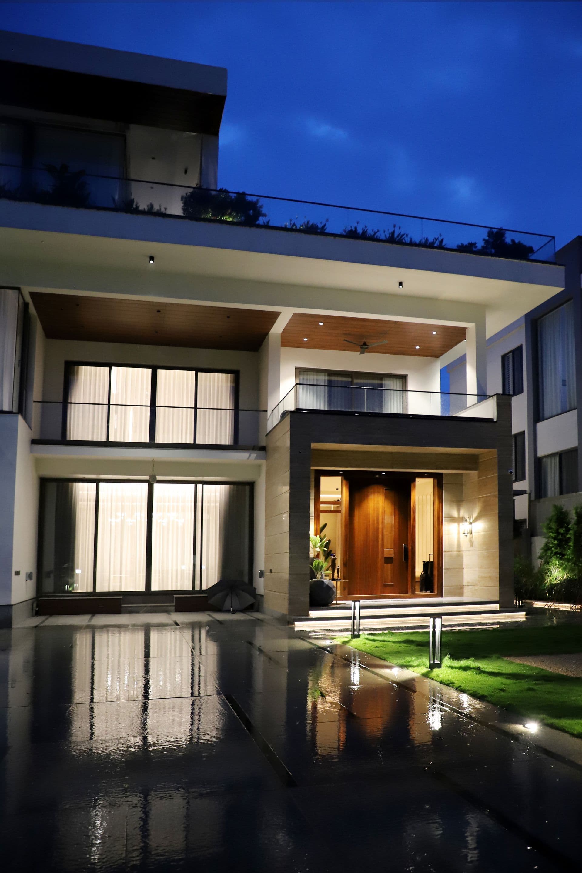 A modern estate lit at night, pool illuminated