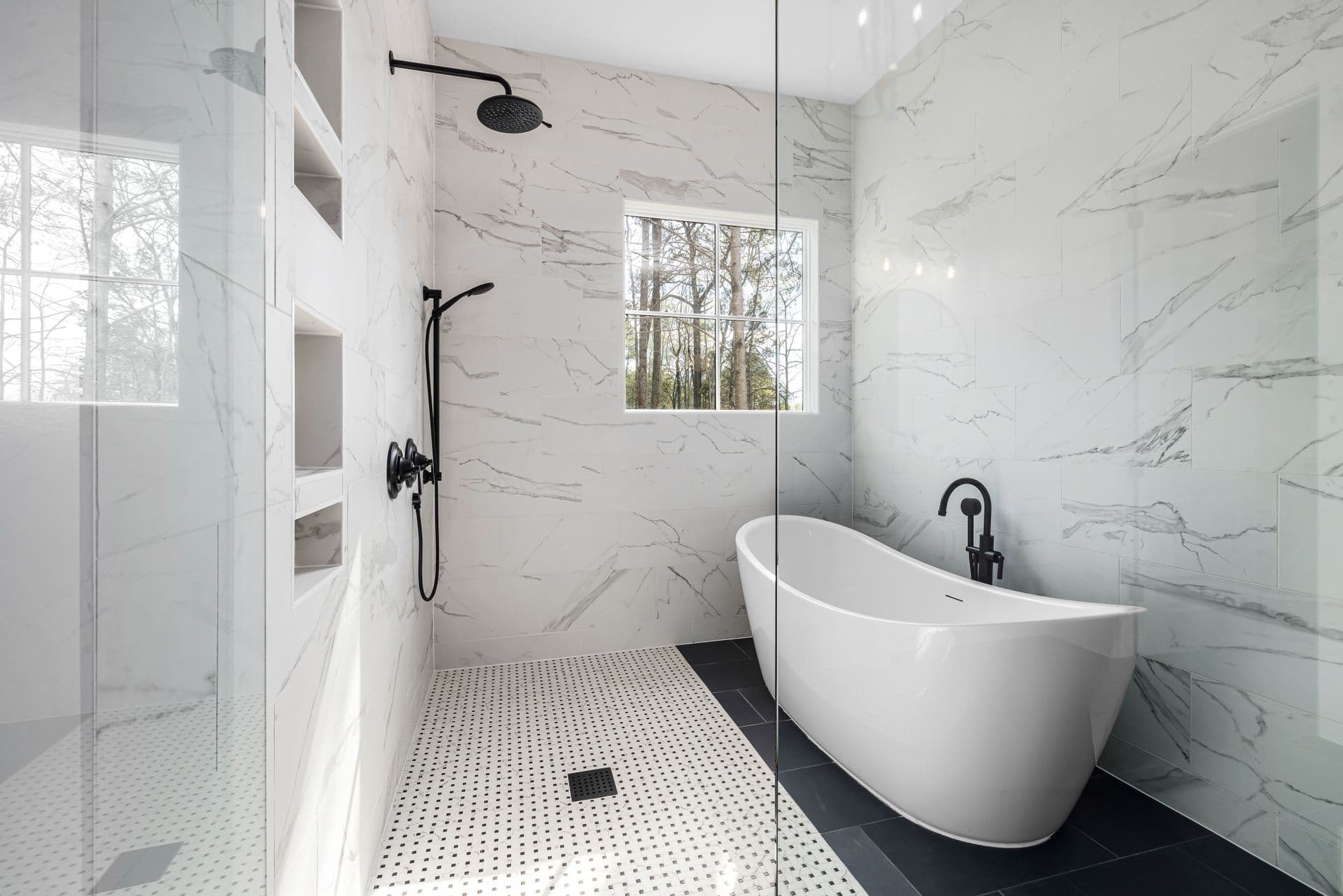 A marble bathroom with a freestanding tub beneath a window
