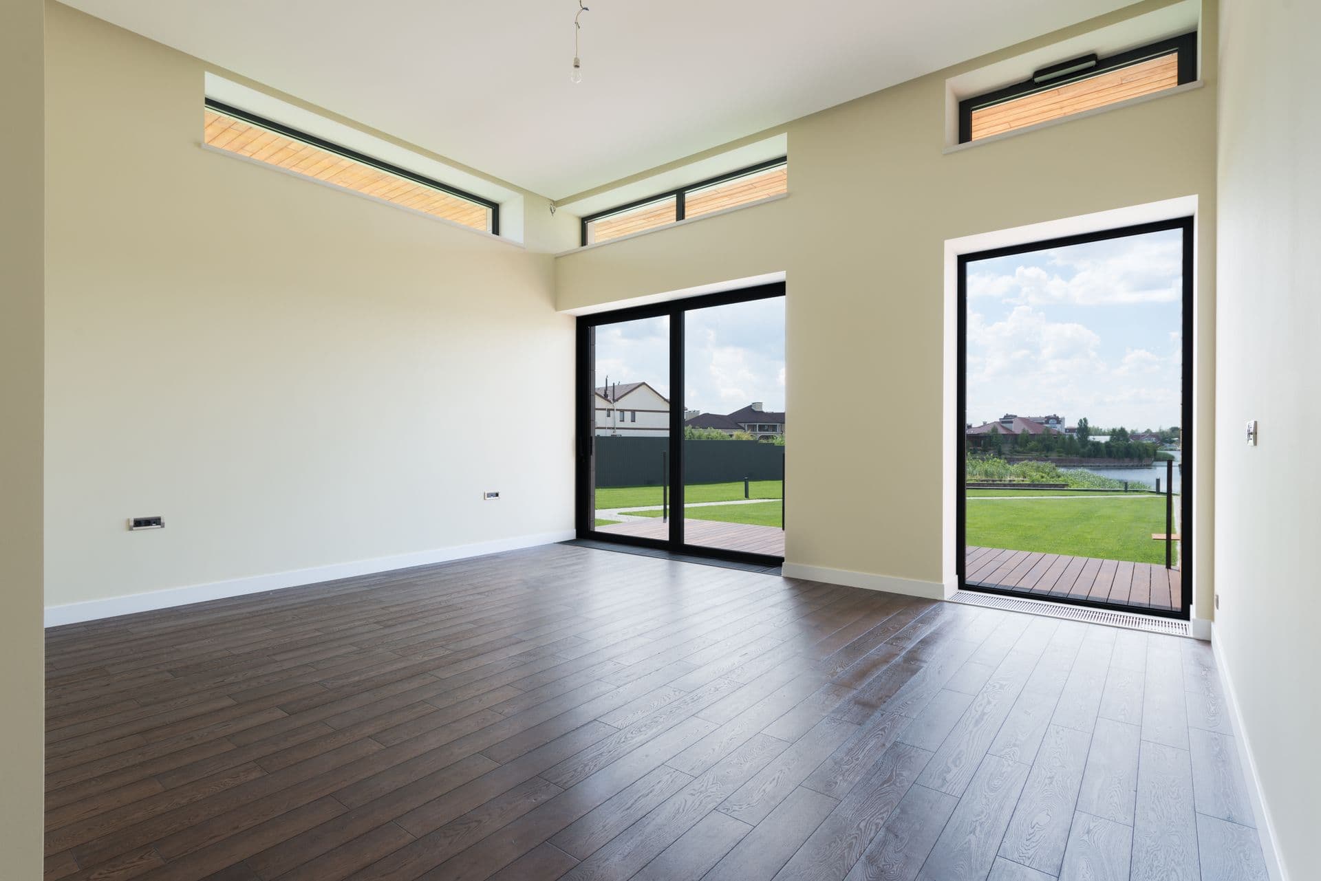 A sunlit living room with floor-to-ceiling glass and a garden view
